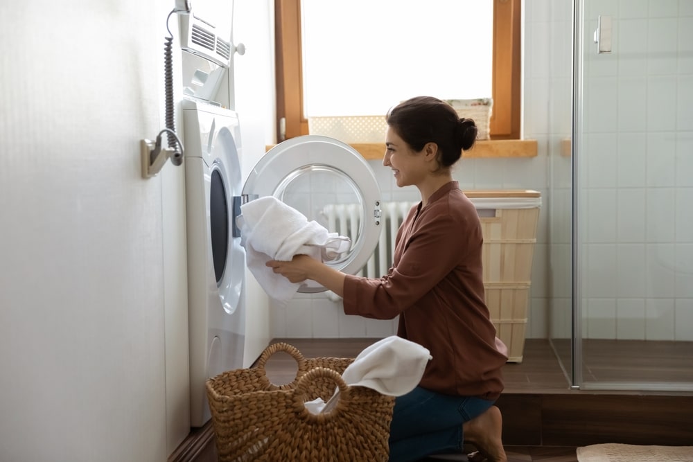 A side view of a lady washing white clothes inside a washing machine