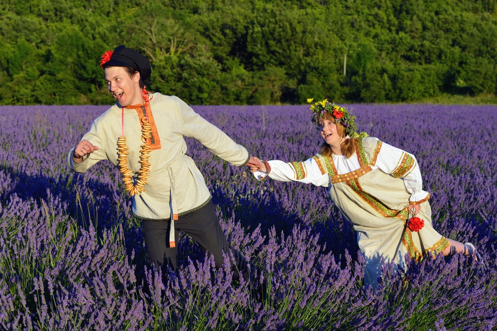 A view of a happy couple in a field wearing russian clothing