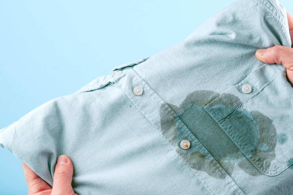 A view of a person holding a shirt with oil stain