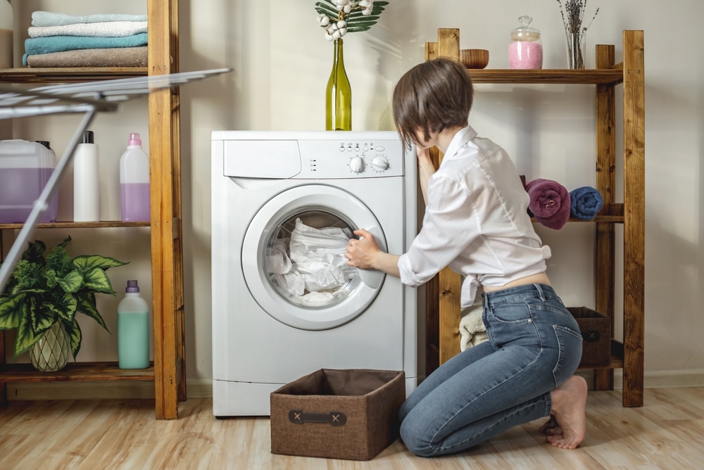 A view of a woman taking clothes out of the washing machine