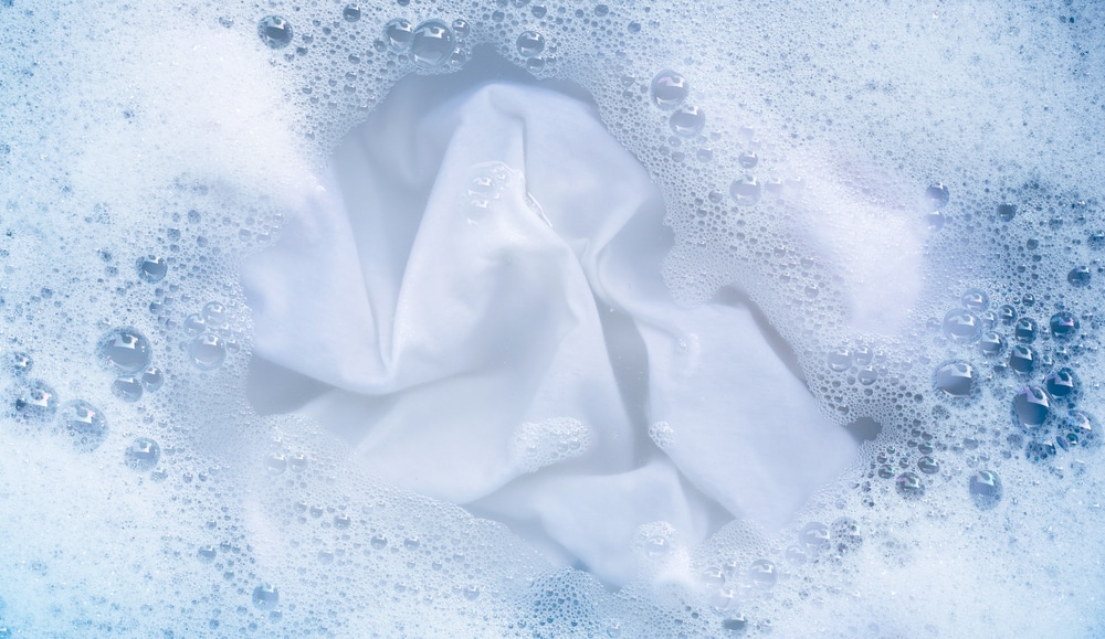 A view of white clothes submerged in soapy water