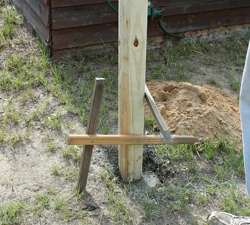 A DIY clothesline in process with dirt around the wooden post