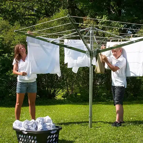 A mother and a son hanging clothes on an outdoor clothesline umbrella