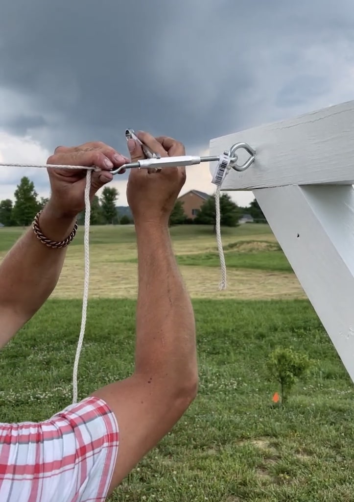 A person inserting the hook into the wooden clothesline post