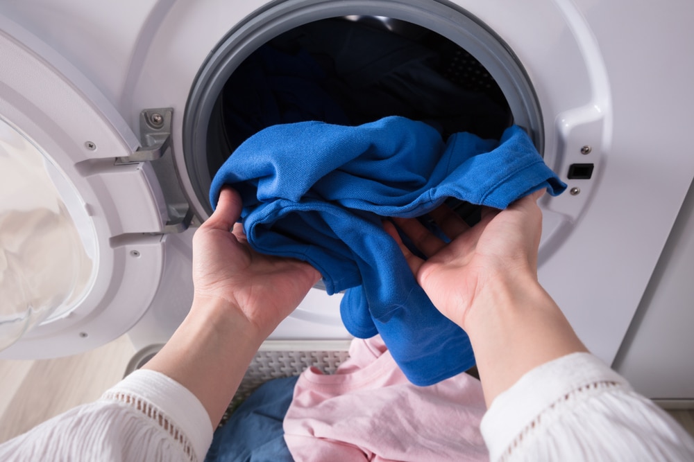 A view of a person taking clothes out of a dryer