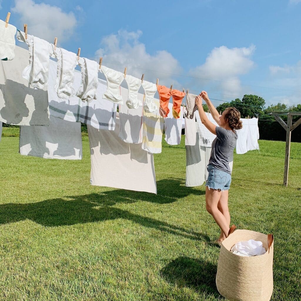 A woman hanging clothes on a clothesline on a bright sunny day