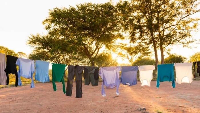 Clothes drying outdoors on a clothesline with sun peeking in through the clothes