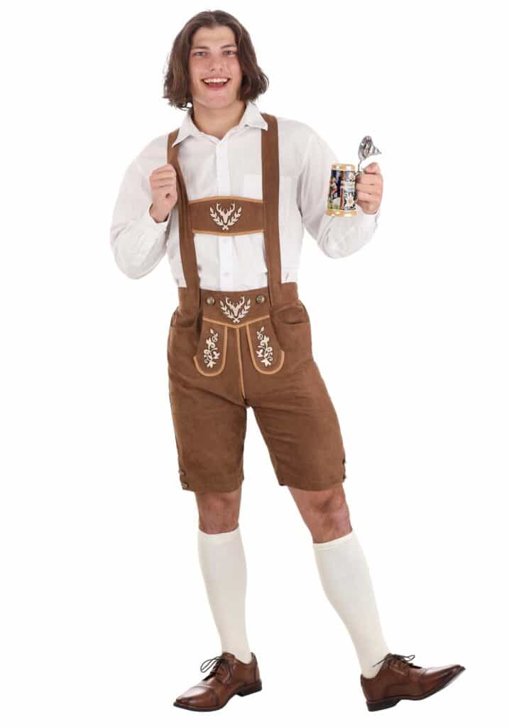 a boy wearing lederhosen in brown and white color with brown shoes holding a cup