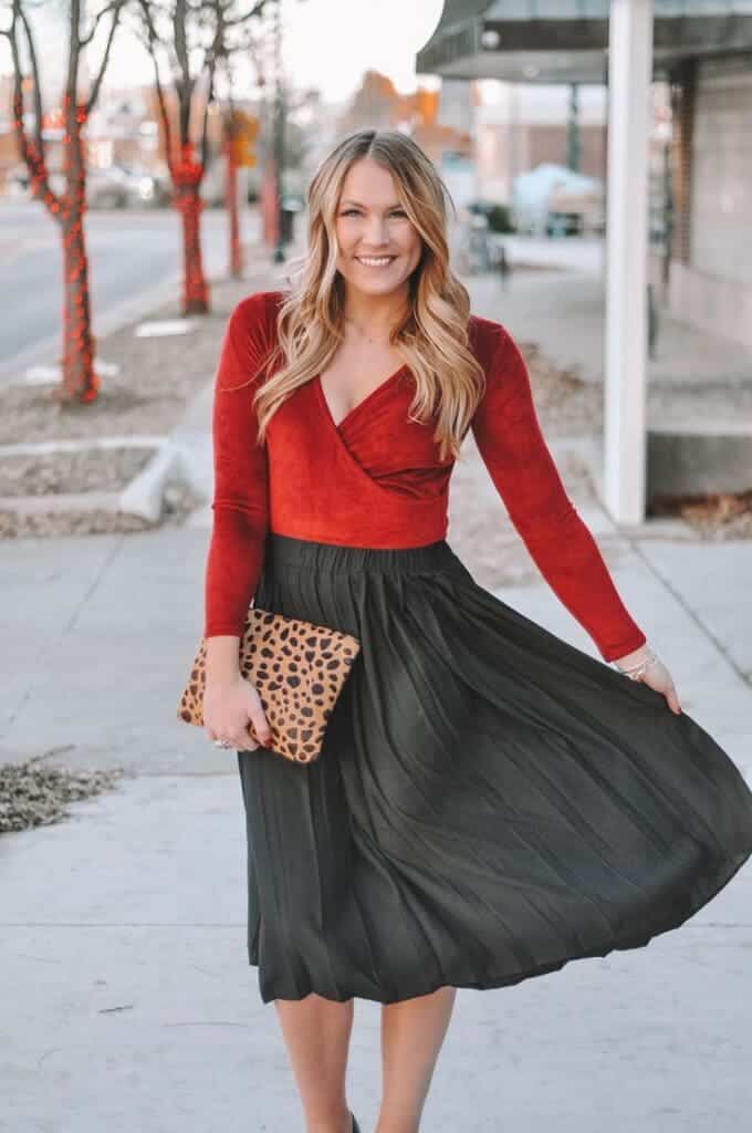 a girl wearing midi skirt with red velvet top standing on the side of road