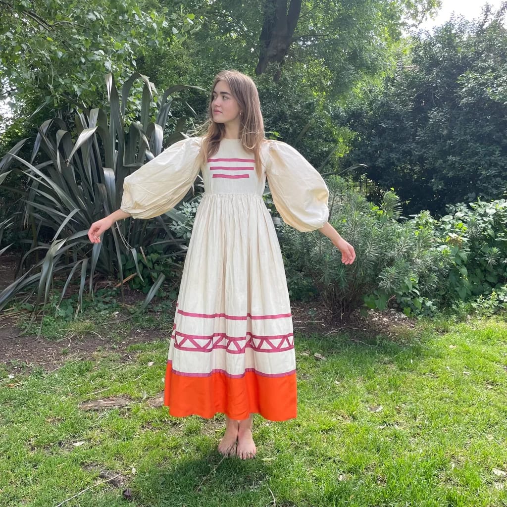 girl styling simple french frock in beige and orange color standing in a lawn