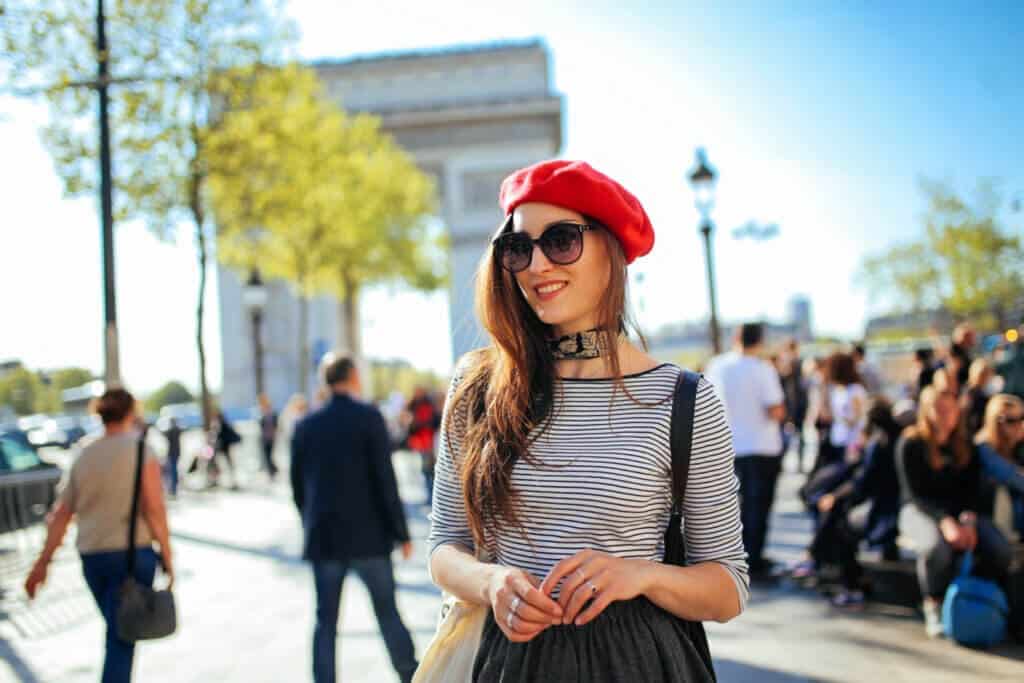 girl wearing sun glasses breton shirt in black and white red hat standing in a crowded place