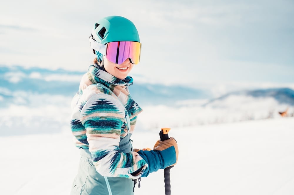 A view of a girl standing in snow wearing helmet and goggles