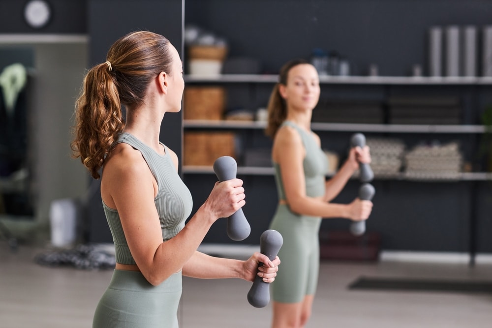 A view of a lady in gym holding dumbells