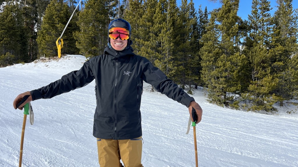 A view of a person wearing a black Arcteryx ski jacket standing in snow