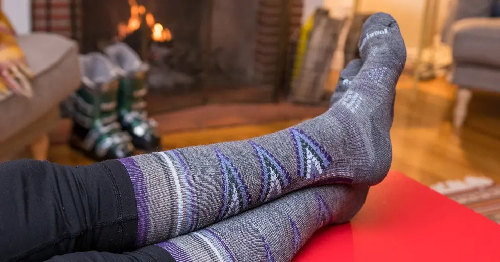 A view of a person wearing purple socks with legs placed on a table