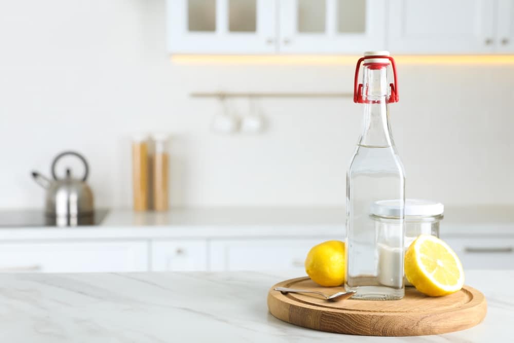 Vinegar, baking soda and lemon on white marble table in kitchen