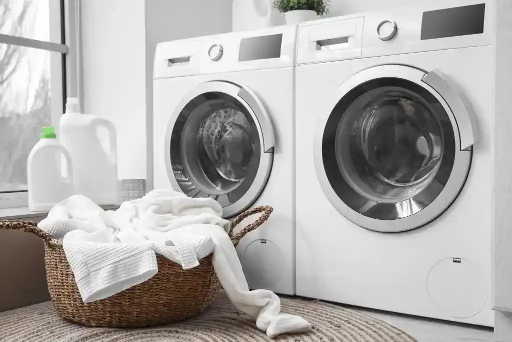 front load washing machines along with a basket of clothes and bleach bottles