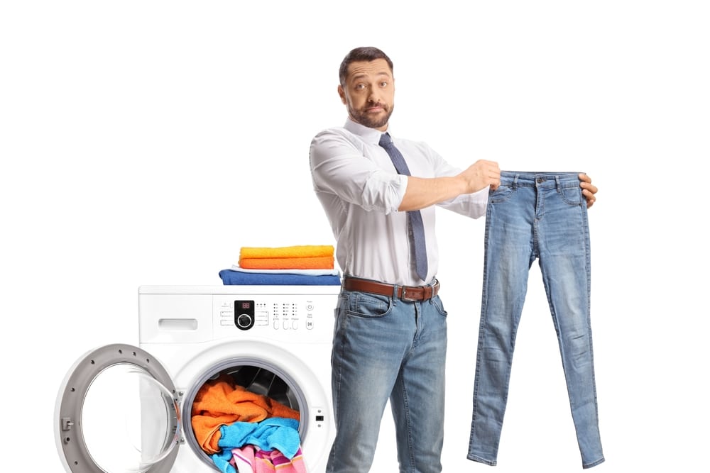 Man Standing In Front Of A Washing Machine And Holding