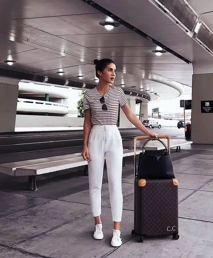 women standing at airport along with suicase