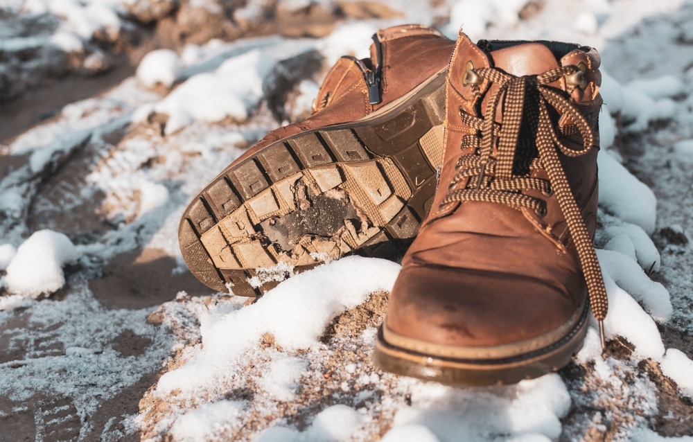 Torn Winter Boots Lie On The Ground With Snow