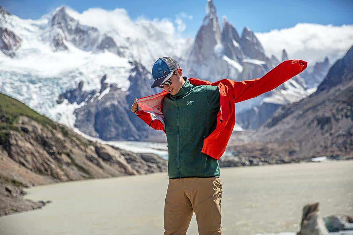 a man standing in front of snowy mountains wearing fleece middle layer