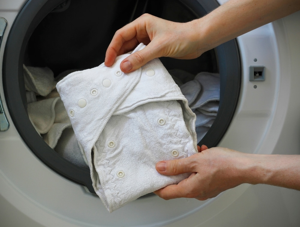 Female Hands Holding A White Cloth Baby Diaper In Front