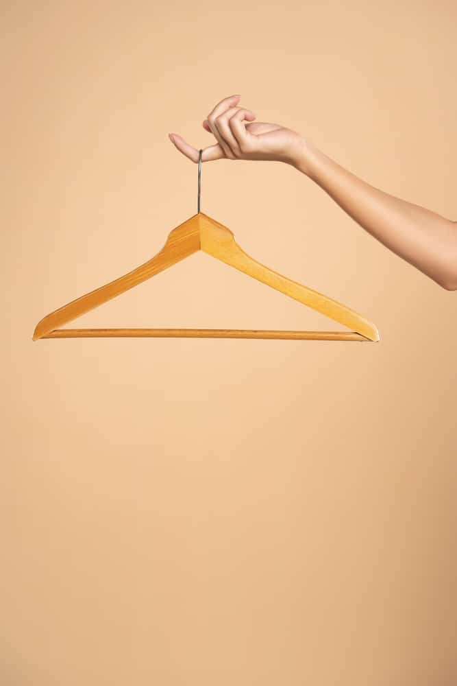 Woman Finger Holding Empty Hanger On A Beige Studio Background