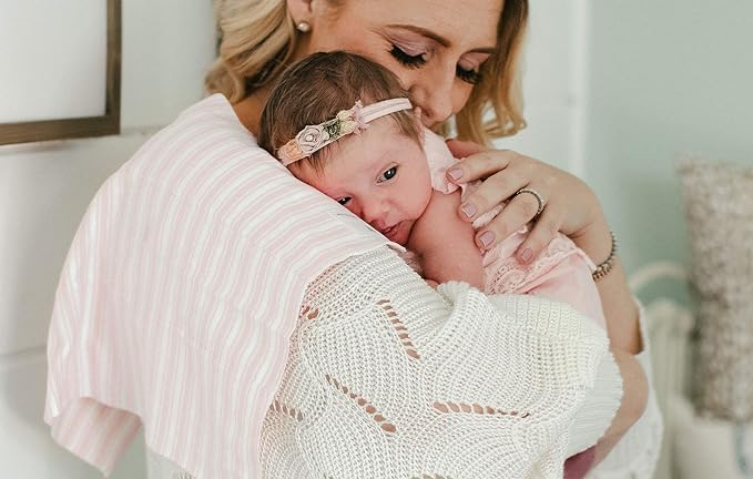 a baby is leaning on mother shoulder along with burp cloth 