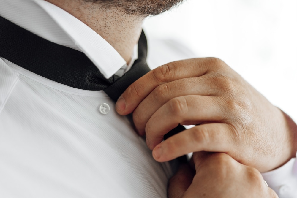 A Man Is Getting Ready To Tie His Tie He