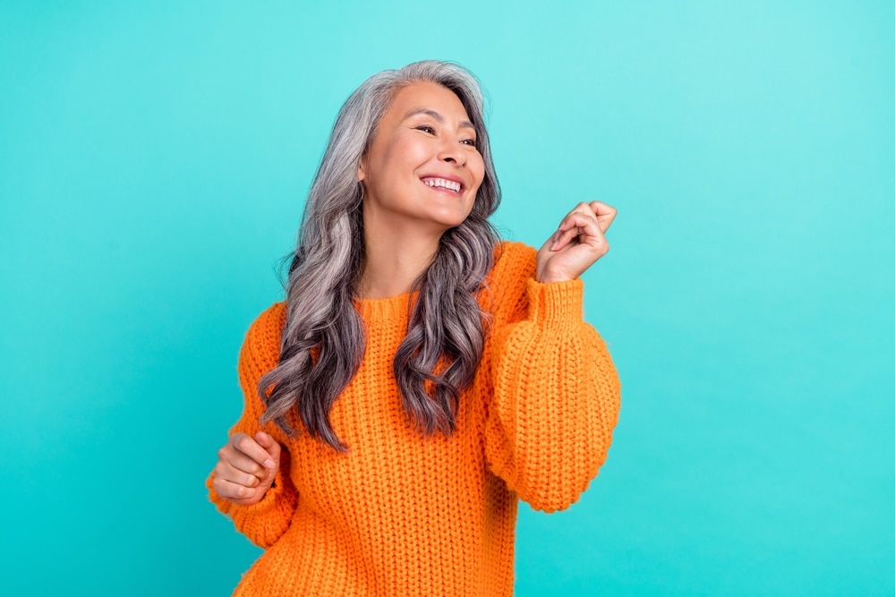 A view of a fun cheerful old lady wearing a trendy orange sweater